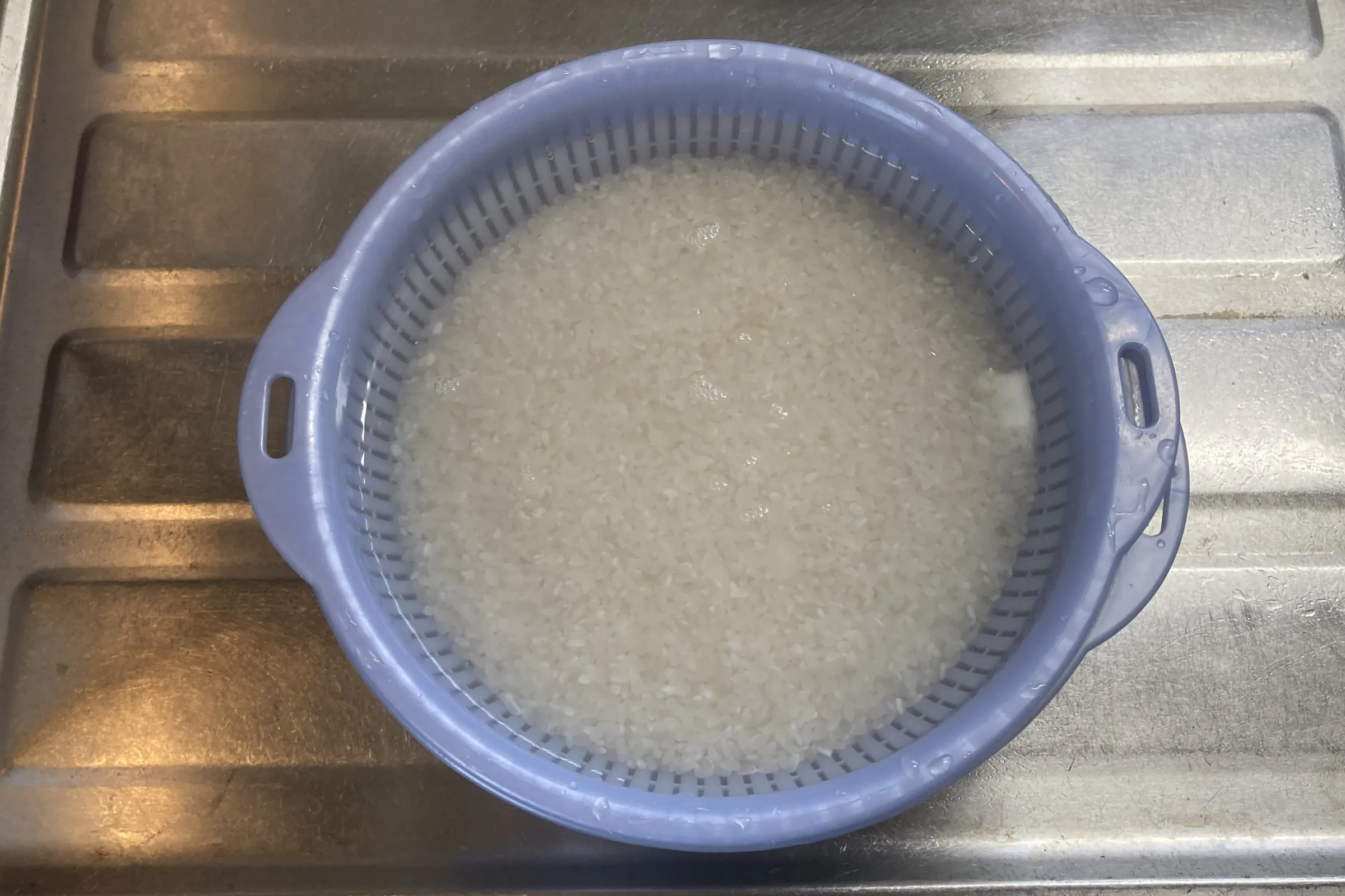 ボウルに入った米を水で研いでいる様子