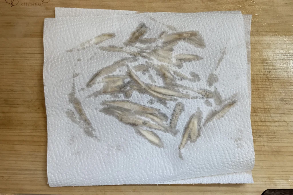 水にさらしてアク抜きをした後、キッチンペーパーで丁寧に水気を拭き取っている細切りのごぼう。ホットクックでの味馴染みを良くし、ベチャッとしない食感に仕上げるための重要な工程。