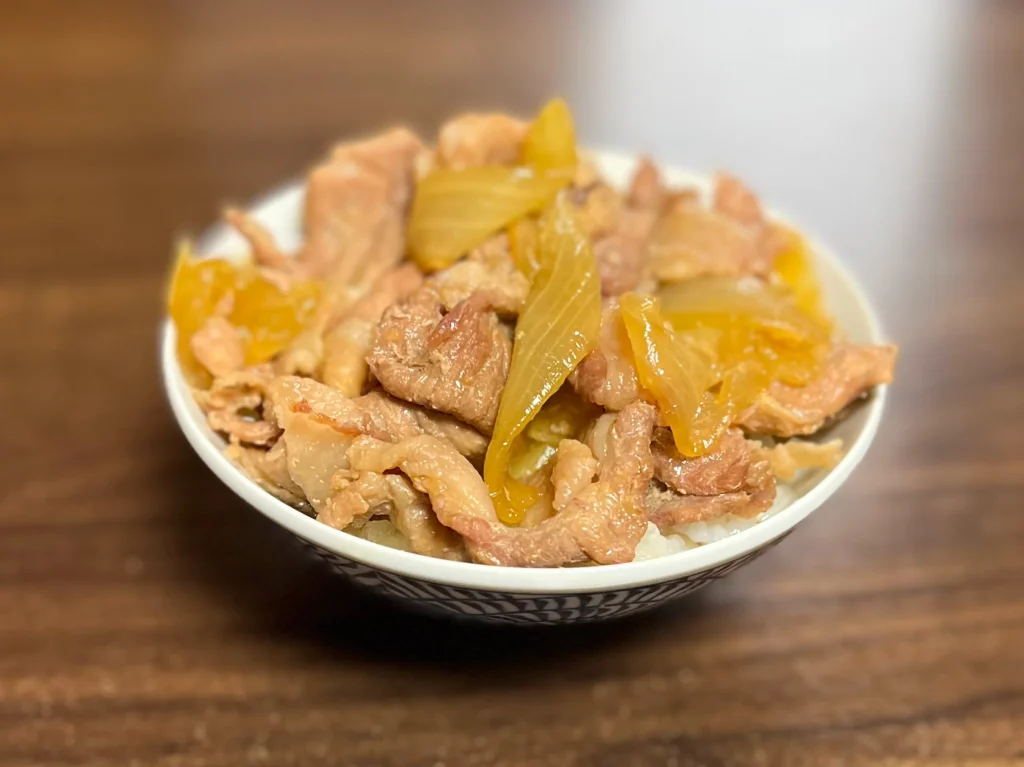白い茶碗に盛り付けられた、つゆだくの豚丼。ホットクックで調理され、味が染みて飴色になった玉ねぎと、柔らかそうな豚薄切り肉がたっぷりとご飯の上に乗っている