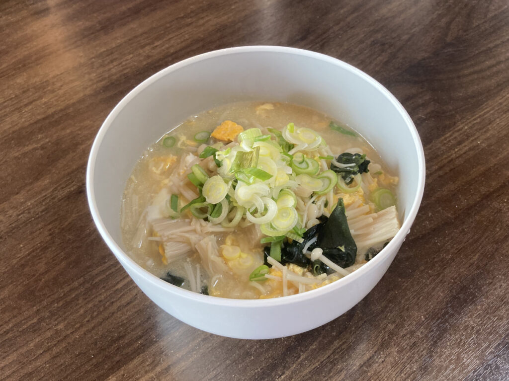 ホットクックの「即席めん」モードを使って調理した、えのきとふんわり溶き卵入りのうまかっちゃんがどんぶりに盛られています。たっぷりのネギがトッピングされ、湯気が立ち上る食欲をそそる完成写真です。
