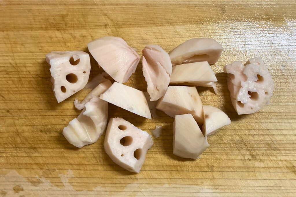 筑前煮用にカットされたれんこん。一口大の乱切りにされており、木製のまな板の上に散らばっている。