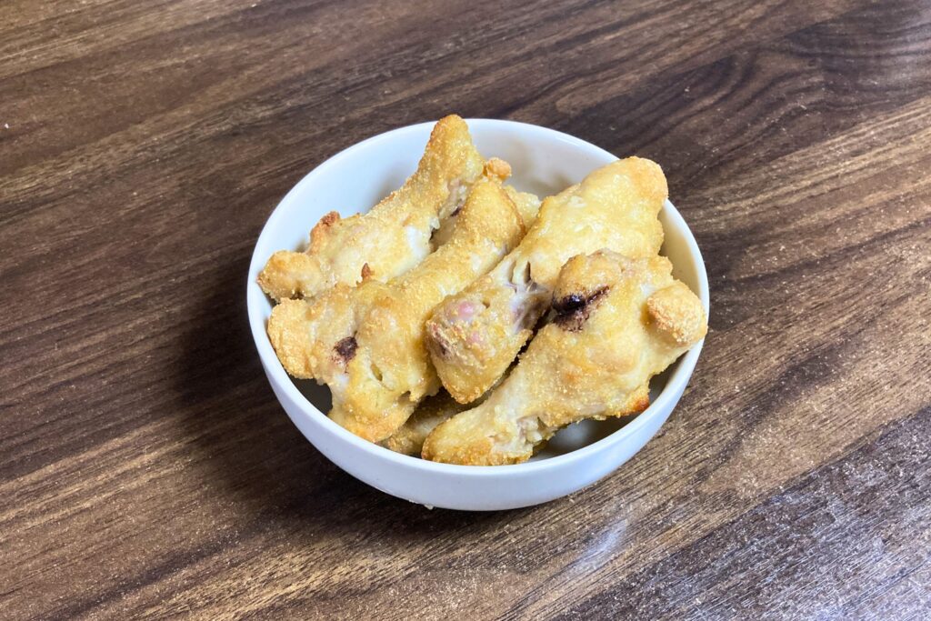 オーブンでキツネ色に香ばしく焼き上げられた鶏手羽元の唐揚げが、白い深めのボウルにこんもりと盛り付けられている様子。