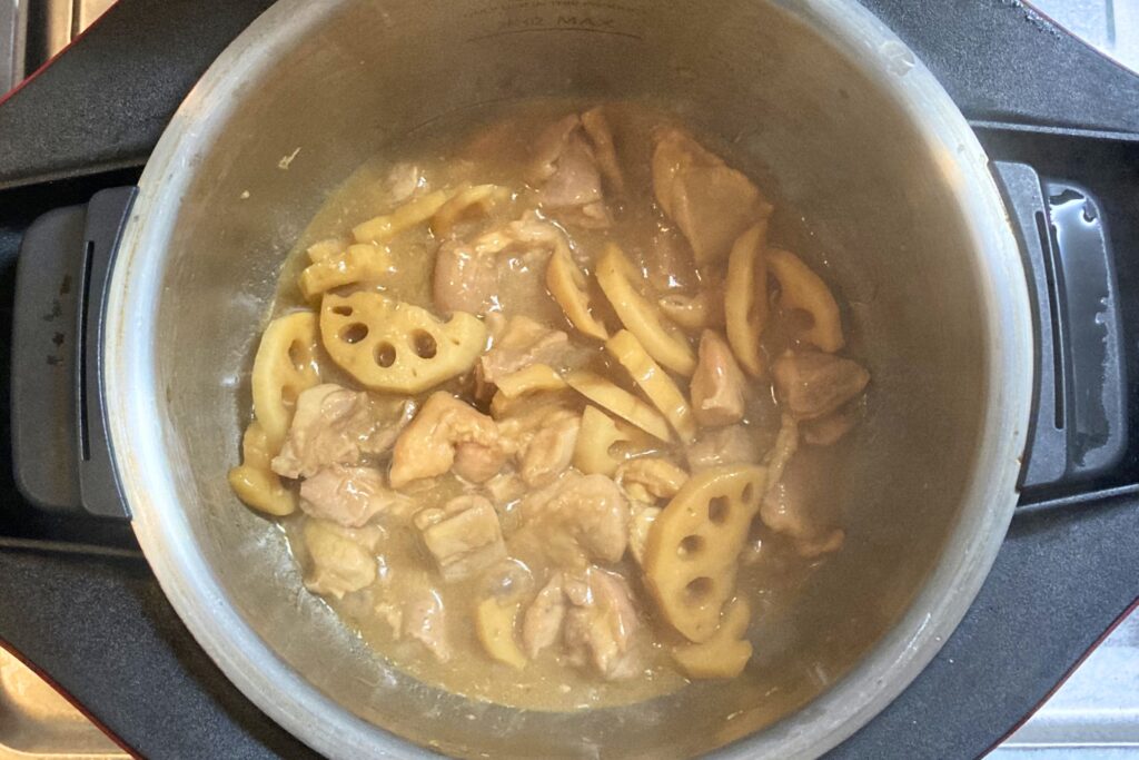 自動調理鍋の中で加熱が完了し、とろみのついたタレが絡んで美味しそうに仕上がった鶏肉とレンコンの炒め物。出来立てで湯気が立っています。