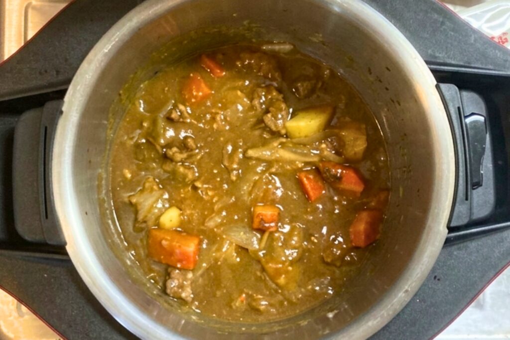 ルーを加えて煮込み工程がすべて完了した自動調理鍋の内鍋。大きめにカットされた豚肉やにんじん、じゃがいもなどの具材に、とろみのある濃厚なカレーがしっかりと絡んでいます。