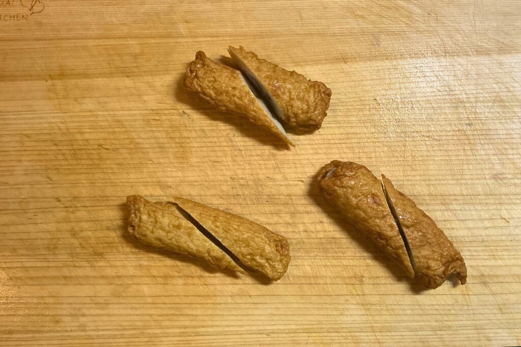 まな板の上で、食べやすいように斜めに半分にカットされた3つのごぼう巻。茶色の練り物の断面から白いごぼうが見えている。