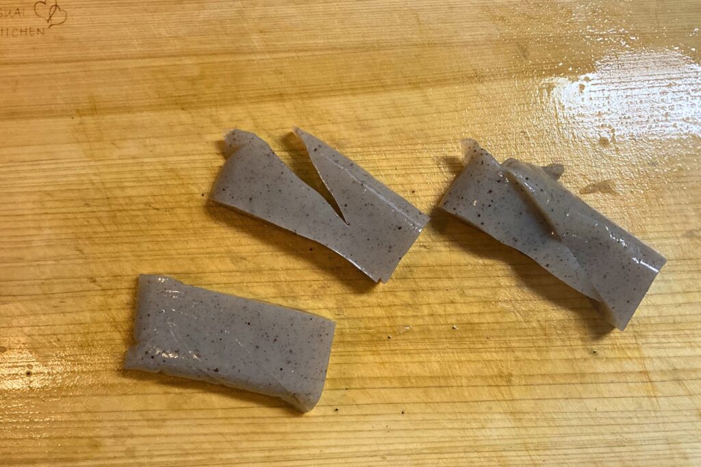 長方形にカットされた灰色のこんにゃく。表面には味が染み込みやすいよう、斜めに細かく隠し包丁が入れられている。