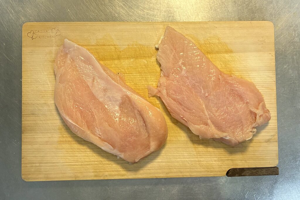 まな板の上に並べた鶏むね肉2枚。右の1枚は観音開きにして厚みを揃えている