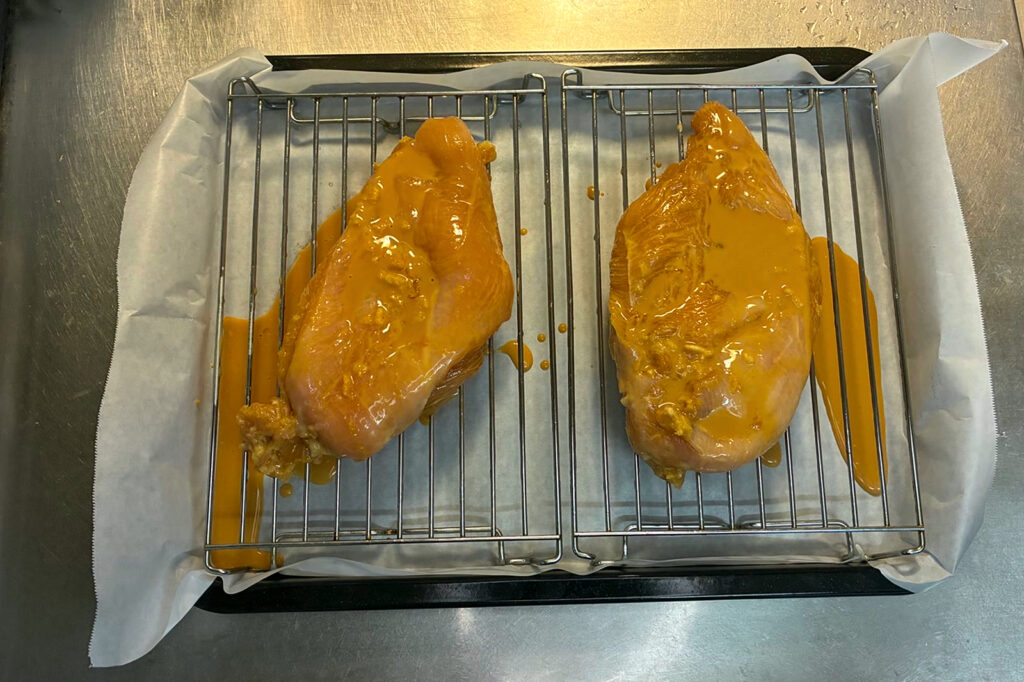 クッキングシートを敷いた角皿に網を2枚置き、タレをからめた鶏むね肉を1枚ずつのせた状態