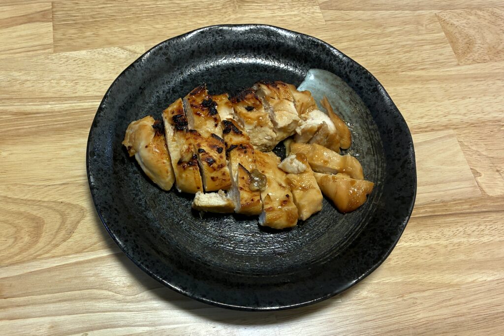 黒い丸皿に盛り付けた、ヘルシオで焼いた甘辛ガーリックの鶏むねステーキ