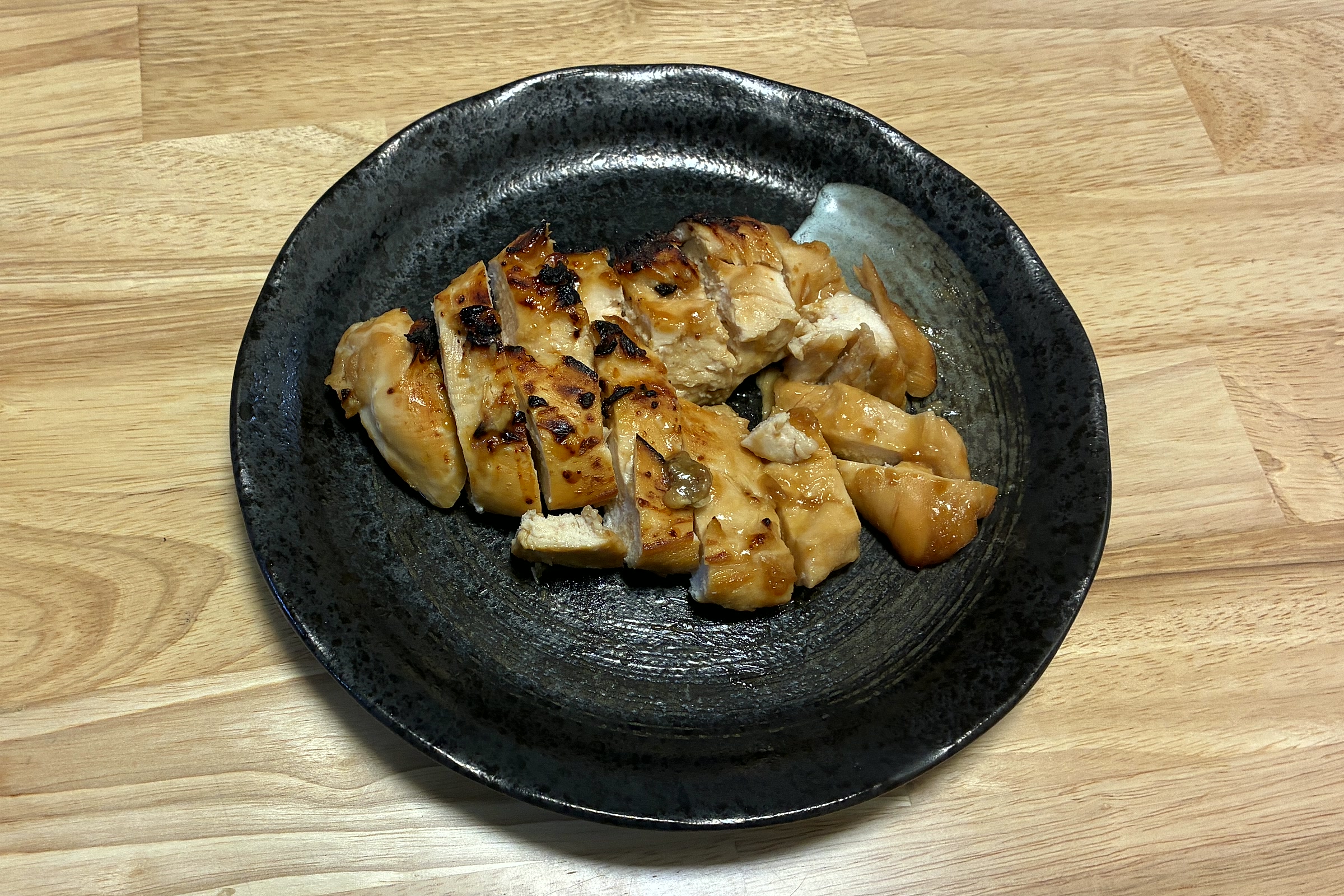 黒い丸皿に盛り付けた、ヘルシオで焼いた甘辛ガーリックの鶏むねステーキ