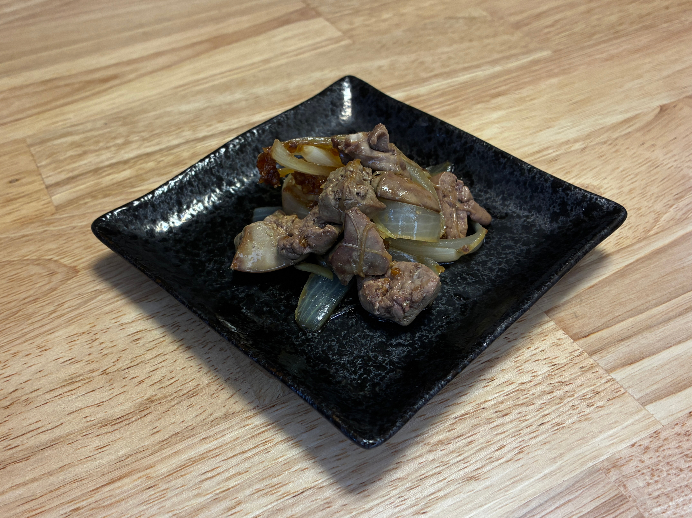ヘルシオの蒸し物機能で作る鶏レバーの甘辛しょうが蒸しの完成写真。臭みなくしっとり仕上がった鶏レバーとハツに照りのある甘辛だれが絡み、黒い和皿に美しく盛られた様子。