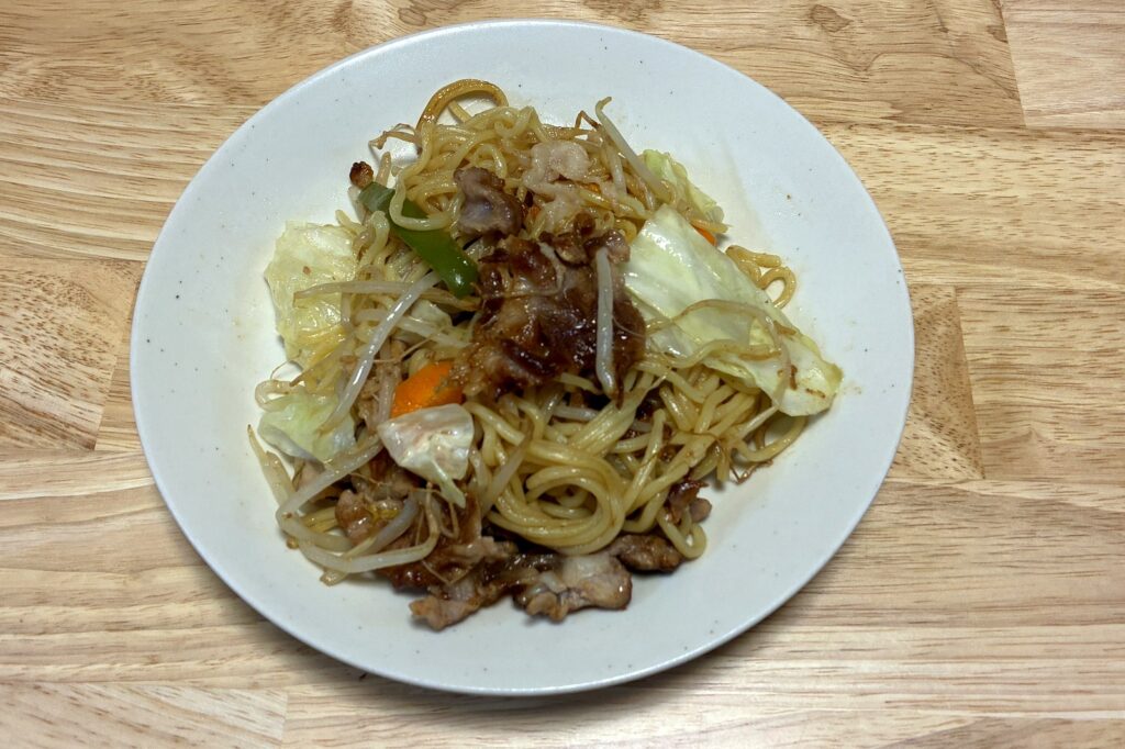 白い皿に盛りつけたヘルシオの焼きそば。豚こま肉とキャベツ、もやし、にんじんが麺とからんでいる。