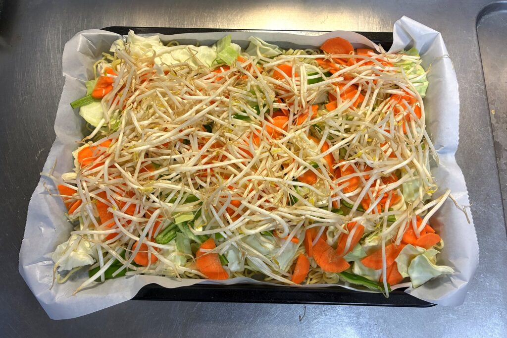 角皿の麺の上に、キャベツ・にんじん・もやしを角皿いっぱいに広げてのせた状態。