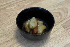 黒い小鉢に盛り付けたホットクックの梅にんにく。ホクホクに蒸したにんにくに梅肉とかつお節が絡んでいる