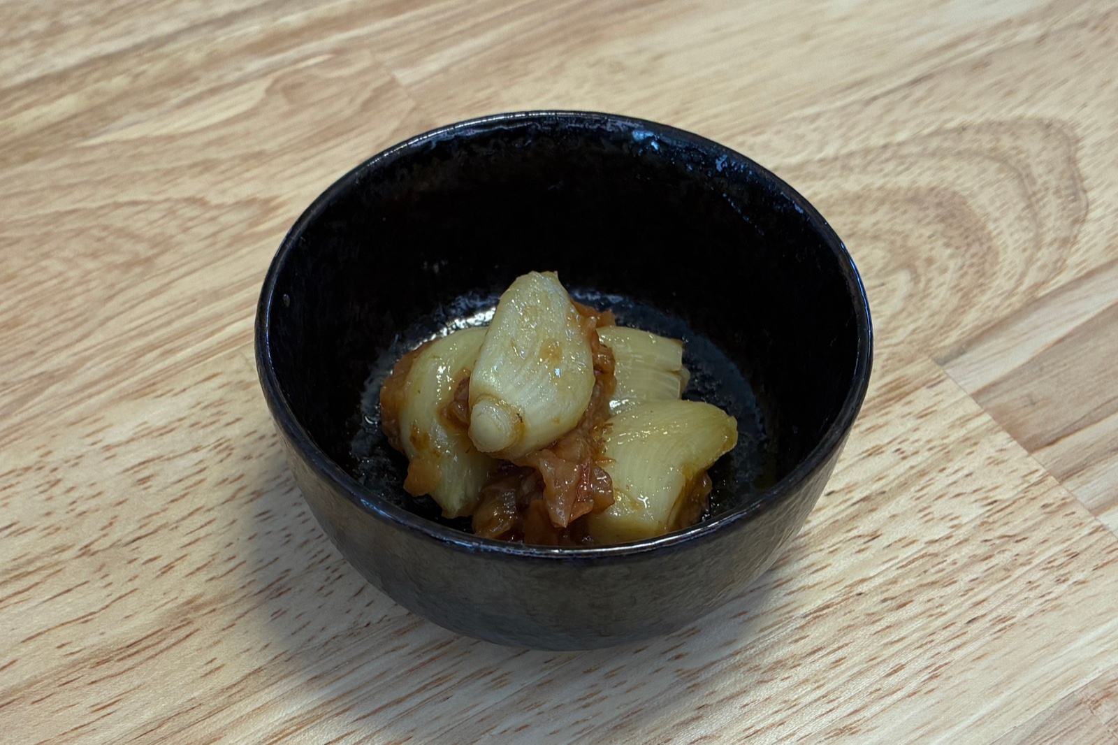 黒い小鉢に盛り付けたホットクックの梅にんにく。ホクホクに蒸したにんにくに梅肉とかつお節が絡んでいる