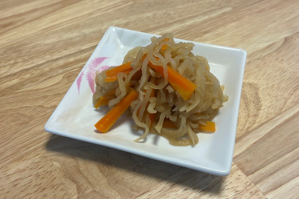 出来上がった切り干し大根の煮物を白い角皿に盛りつけたところ。にんじんの細切りが上に見えている