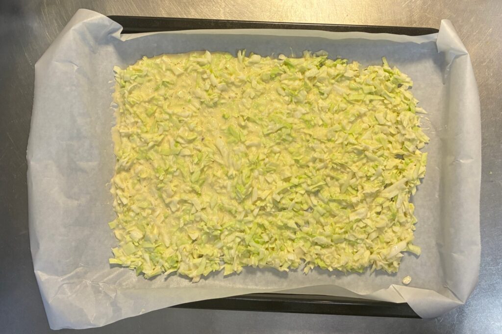 クッキングシートを敷いた角皿に、お好み焼きの生地を四角く平らに広げたところ